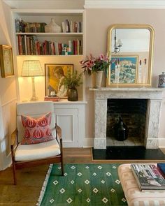 a living room filled with furniture and a fire place covered in books on top of a hard wood floor