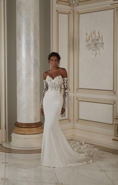 a woman in a white wedding dress standing next to a pillar and chandelier