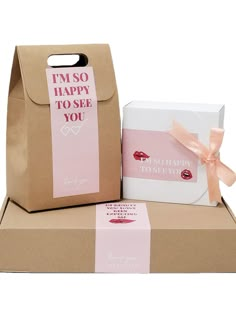 two brown boxes with pink and white designs on them, one has a gift box in the shape of a shopping bag