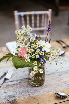 a vase filled with flowers sitting on top of a table next to a fork and knife