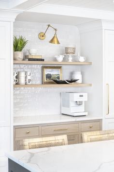 a white kitchen with open shelving and marble counter tops, gold accents on the shelves