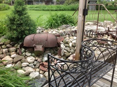 an iron garden bench sitting on top of a rock covered ground next to a lush green field