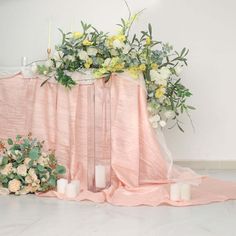 flowers and candles sit on the floor next to a pink table cloth with white roses