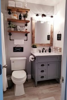 a white toilet sitting next to a sink in a bathroom under a wooden framed mirror