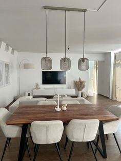 a dining room table with four chairs and a television on the wall in the background