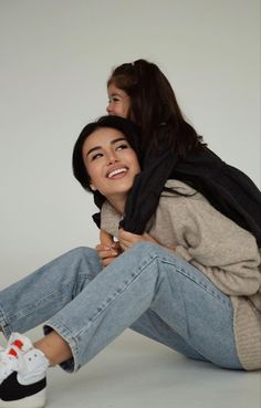 two women are sitting on the floor with their arms around each other and one is smiling