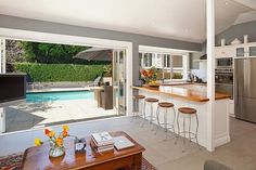 an open kitchen and living room area with sliding glass doors leading to the backyard pool