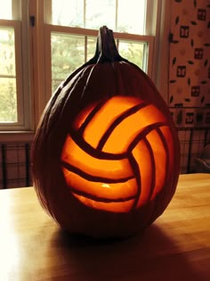 a carved pumpkin sitting on top of a table with a volleyball ball in the center