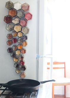 an iron skillet sitting on top of a stove next to a wall hanging with pots and pans