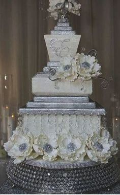 a wedding cake with white flowers and silver decorations on it's tiered tower