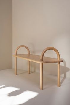 a wooden bench sitting on top of a white floor next to a shadow filled wall