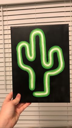 a hand holding up a sticker with a neon green cactus on it