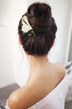 a woman with a flower in her hair is wearing a white dress and looking into the mirror