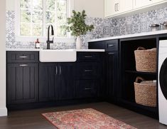 a washer and dryer in a kitchen with black cabinets, white counter tops and wooden floors