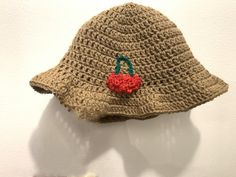 a crocheted hat with a red heart on the front and green handle hanging from it's brim