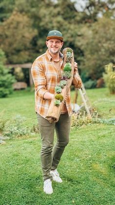 a man standing on top of a lush green field holding a bag filled with plants