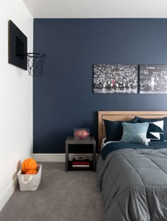 a bedroom with blue walls and grey carpeting, two pictures on the wall above the bed