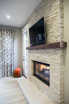 a living room with a fireplace and tv mounted on the wall next to a window