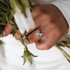 a close up of a person's hand with a ring on top of flowers