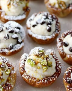 many small pastries are covered with powdered sugar and pistachio toppings