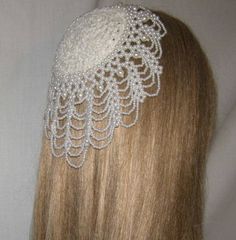 the back of a woman's head wearing a hair piece with pearls on it