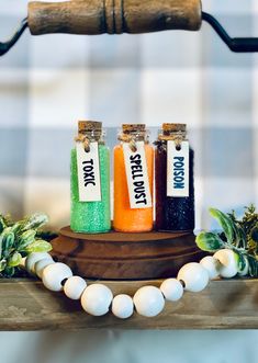 three bottles of different colored liquid sitting on top of a wooden table next to beads