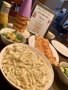 a table topped with plates of food and bowls of pasta next to a sign that says new year's eve