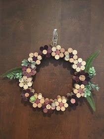 a wreath made out of wine corks on a wooden surface with ferns and leaves