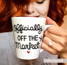 a woman with red hair is holding a coffee cup that says officially off the market