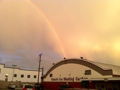 a double rainbow over a building with cars parked in the parking lot