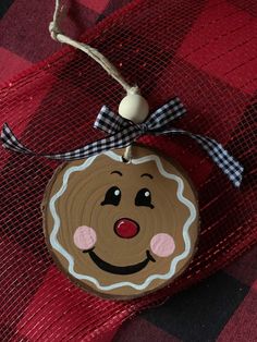 a wooden ornament hanging on a red and black checkered cloth with a smiling face