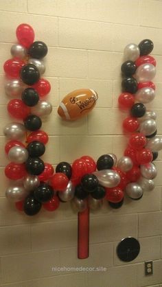 an image of balloons and footballs in the shape of a wreath on a wall