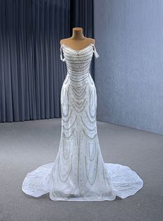 a white wedding dress on display in front of a curtain