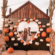 two girls are standing in front of a house made out of pumpkins and hay