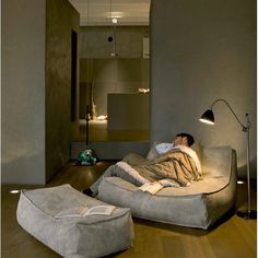 a man laying on top of a couch in a living room next to a lamp