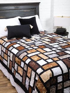 a bed with two black pillows on top of it next to a white brick wall