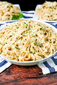 a white bowl filled with pasta on top of a blue and white striped table cloth