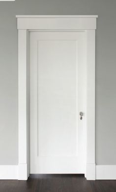 an empty room with a white door and hard wood floor