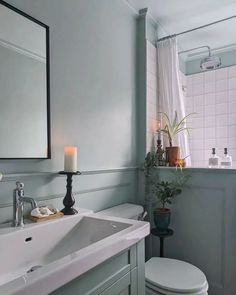 a white toilet sitting next to a sink in a bathroom under a mirror above it