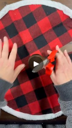 someone using scissors to cut fabric on a buffalo plaid tablecloth with red and black flannel