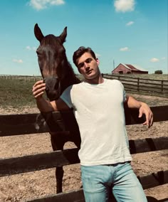 a man standing next to a horse in a fenced in area on a sunny day