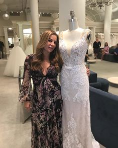 a woman standing next to a dress on a mannequin in a room filled with people