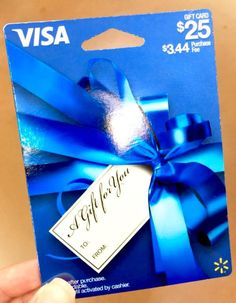 a person holding up a visa gift card with a blue ribbon and bow on it