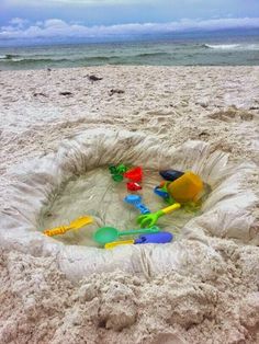 a sand castle on the beach with toys in it