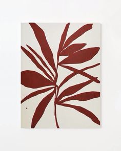 a red and white painting with leaves on the bottom half of it, against a white wall