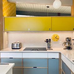 a kitchen with yellow cabinets and white counter tops