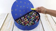 a blue box filled with lots of crayons on top of a wooden table