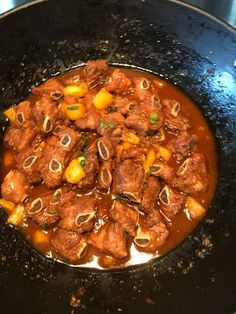 meat and vegetables are being cooked in a wok on the stove top, ready to be eaten