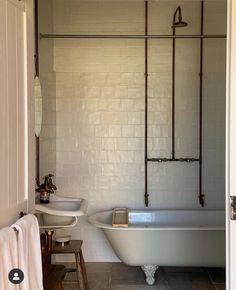 an old fashioned bathtub and sink in a bathroom with white tile walls, flooring and exposed pipes