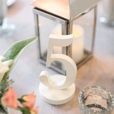 the number five candle holder is next to a vase with flowers and candles on it